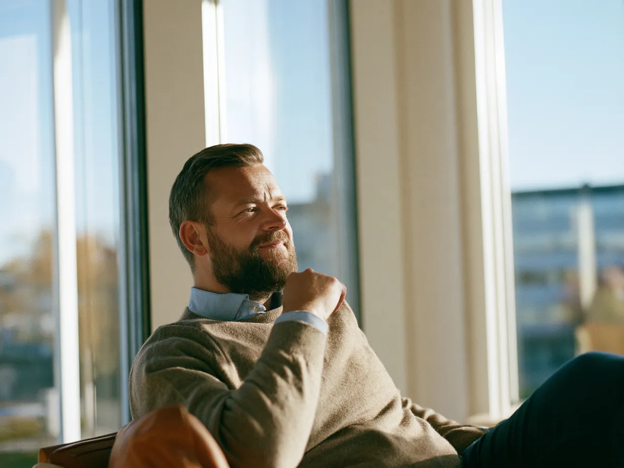 Man sitter avslappnad i ett ljust mottagningsrum och ser ut genom fönstret